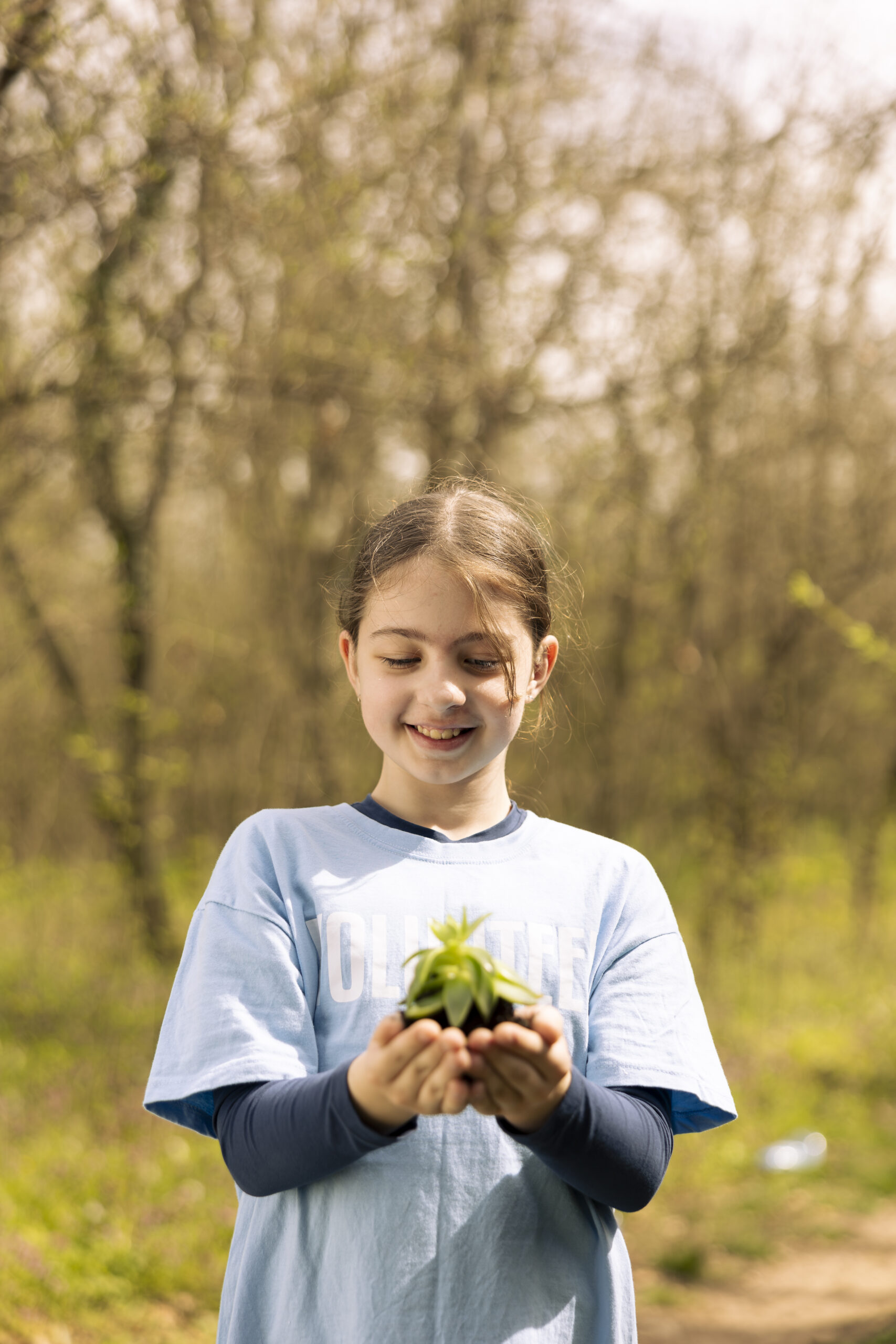 Youngster fighting for forest ecosystem by holding a green seedling with soil, advocating for a sustainable lifestyle. Small girl dedicating her time to help with ecological justice, save the planet.